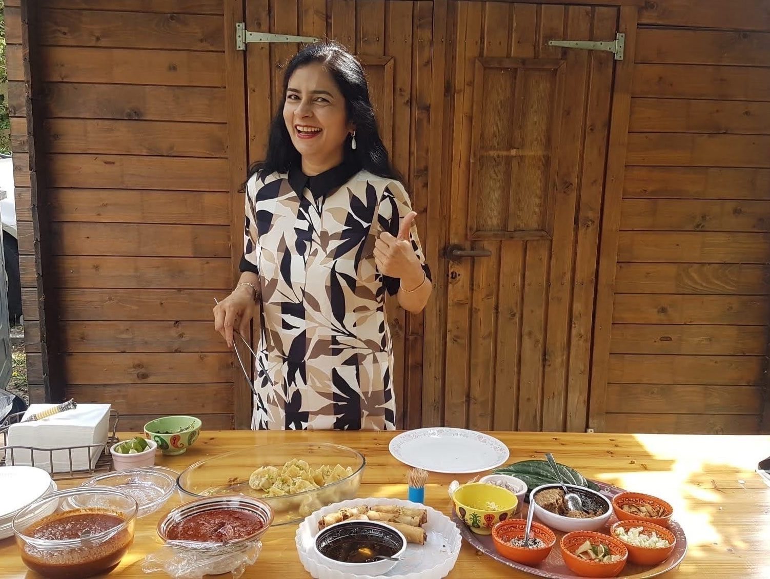 A lady standing behind a table with some food on it