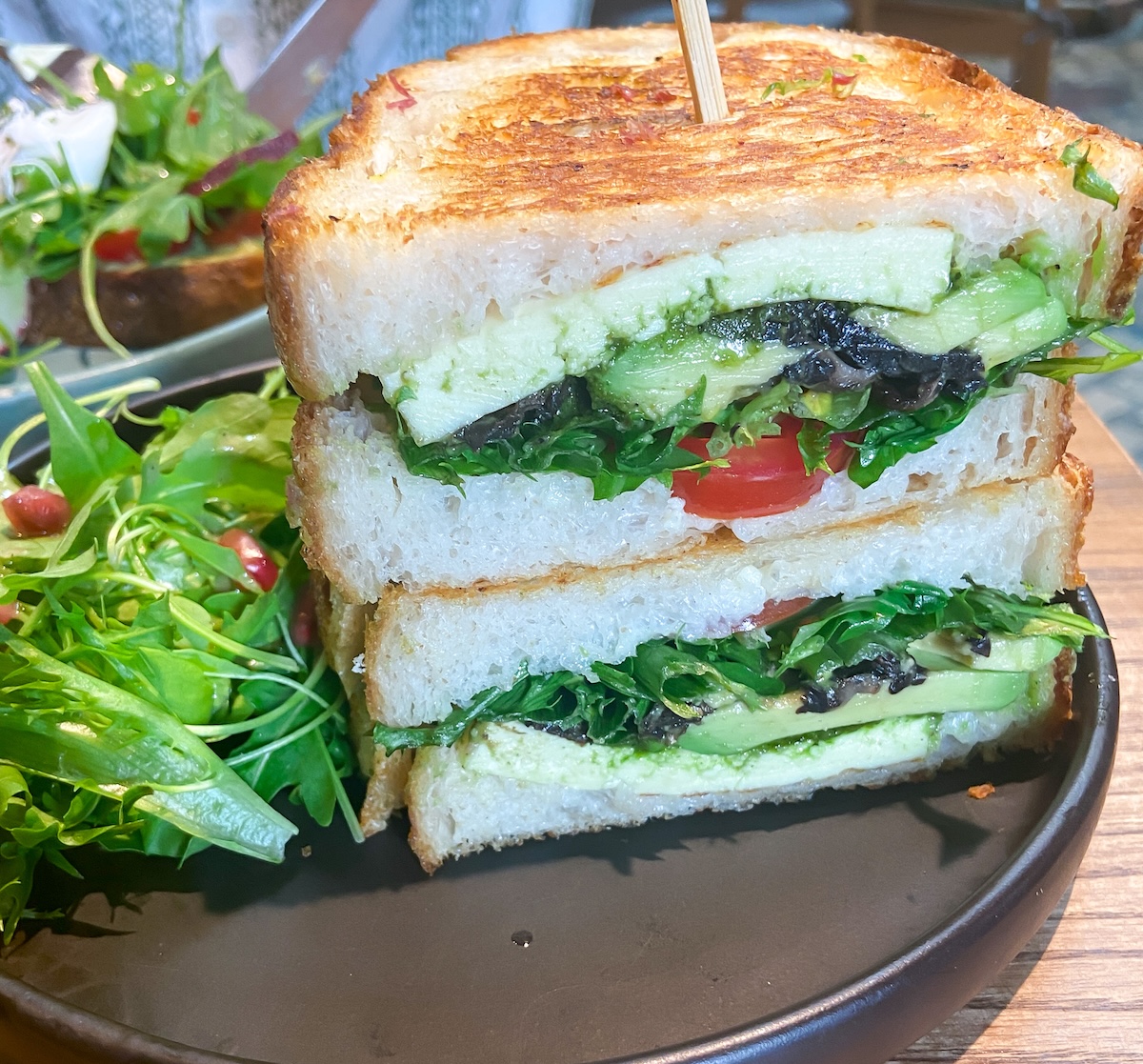 A pesto and halloumi sandwich served with greens