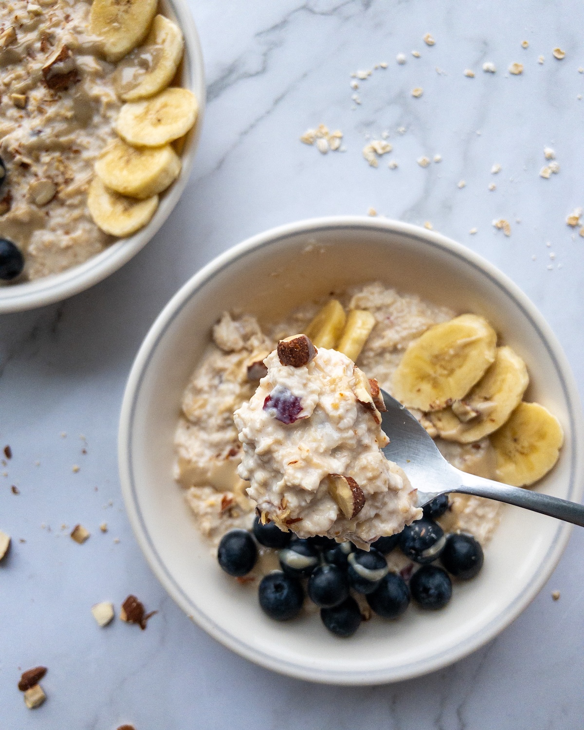 Bircher muesli in a bowl topped with blueberries and banana on a spoon