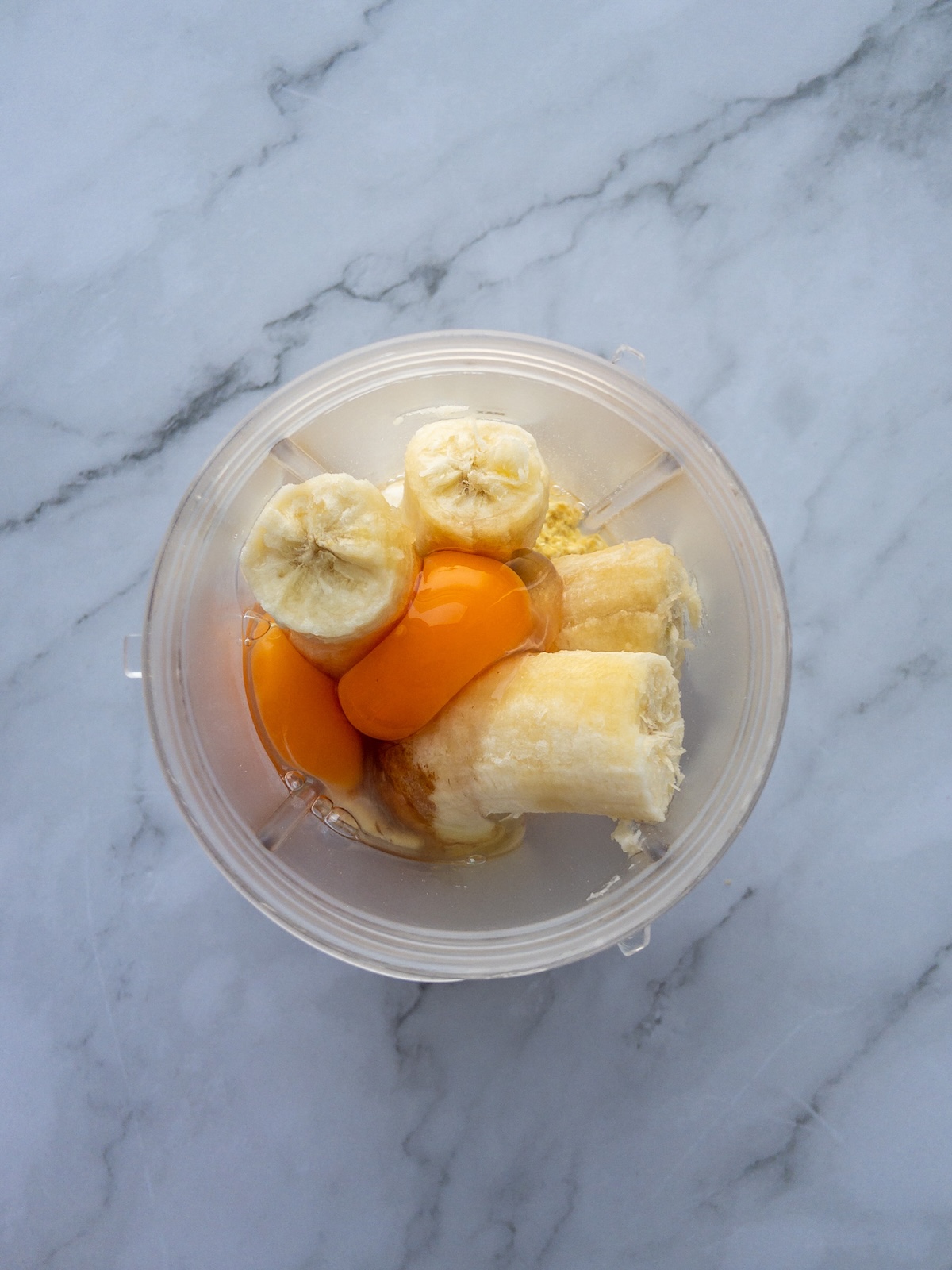 Ingredients for banana pancakes added to a blender. Includes oats, eggs, milk and bananas