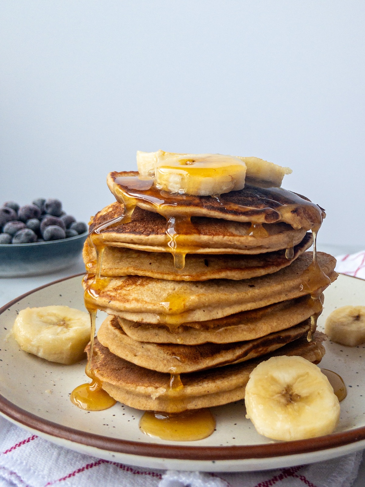 A stack of banana pancakes with maple syrup drizzled on top.