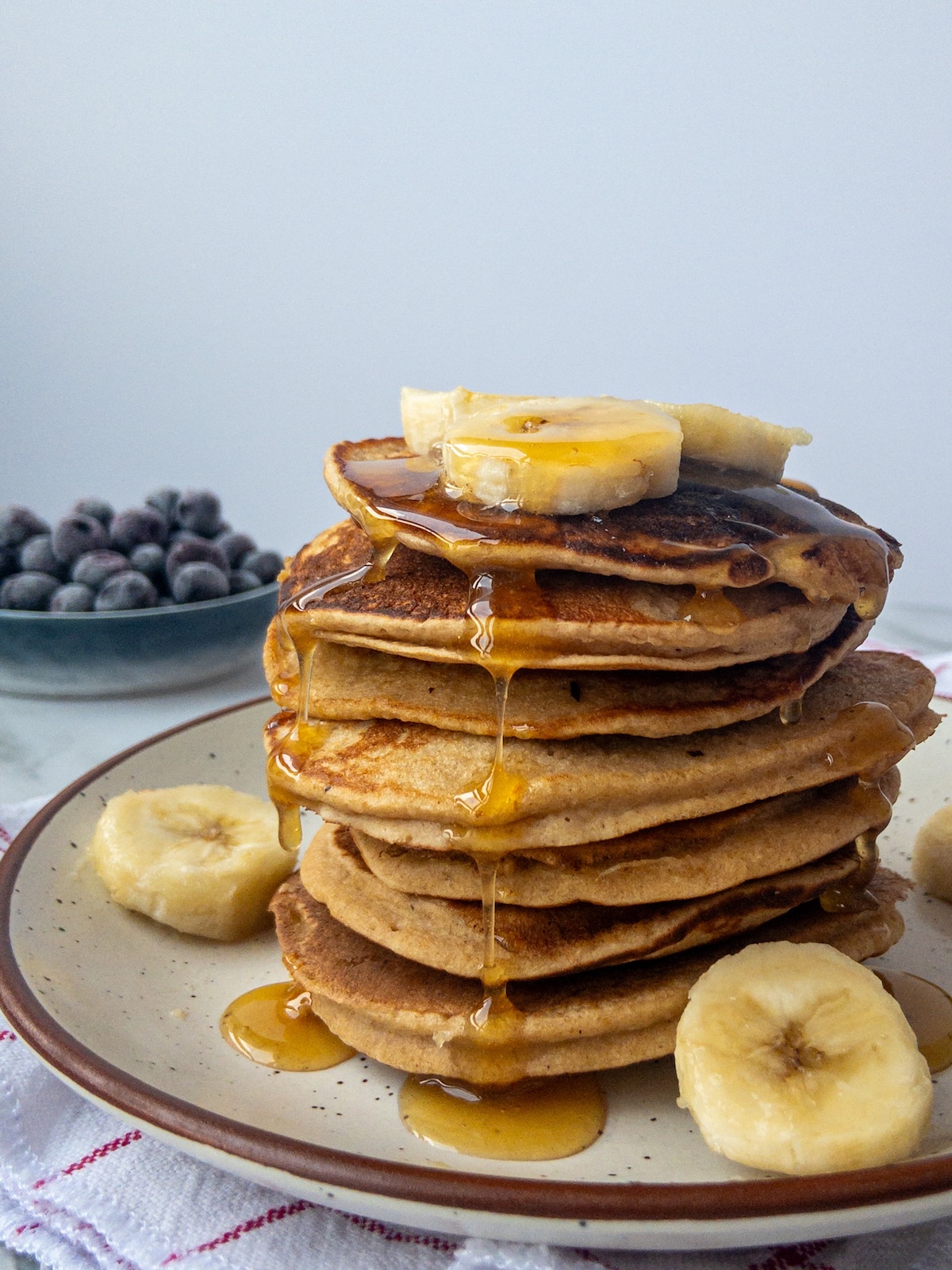 A stack of banana pancakes with maple syrup drizzled on top.
