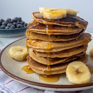 A stack of banana pancakes with maple syrup drizzled on top.