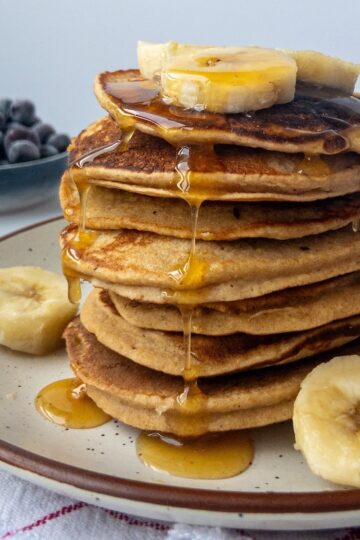 A stack of banana pancakes with maple syrup drizzled on top.