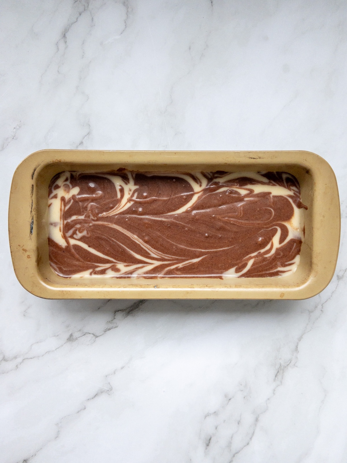 Vanilla and chocolate marbled cake batter mixed in swirls
