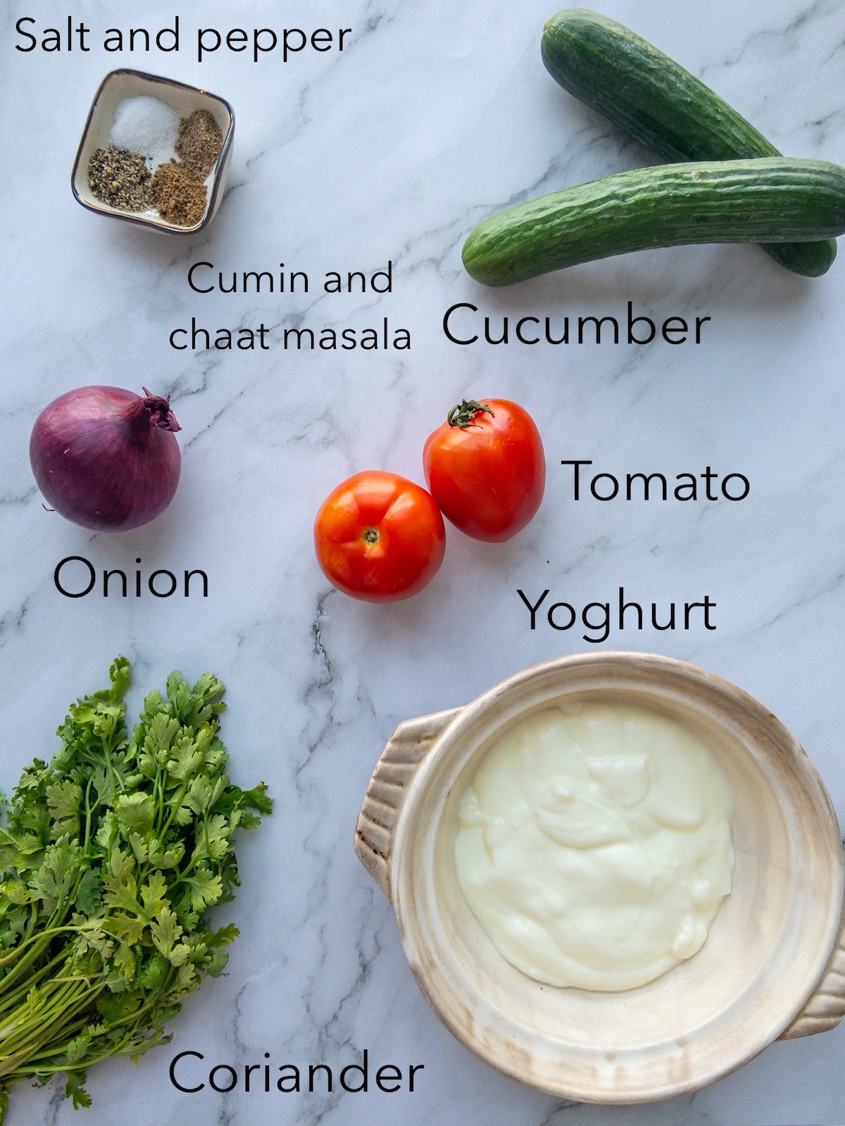 Ingredients for mixed raita on the table - including cucumber, yoghurt and tomatoes