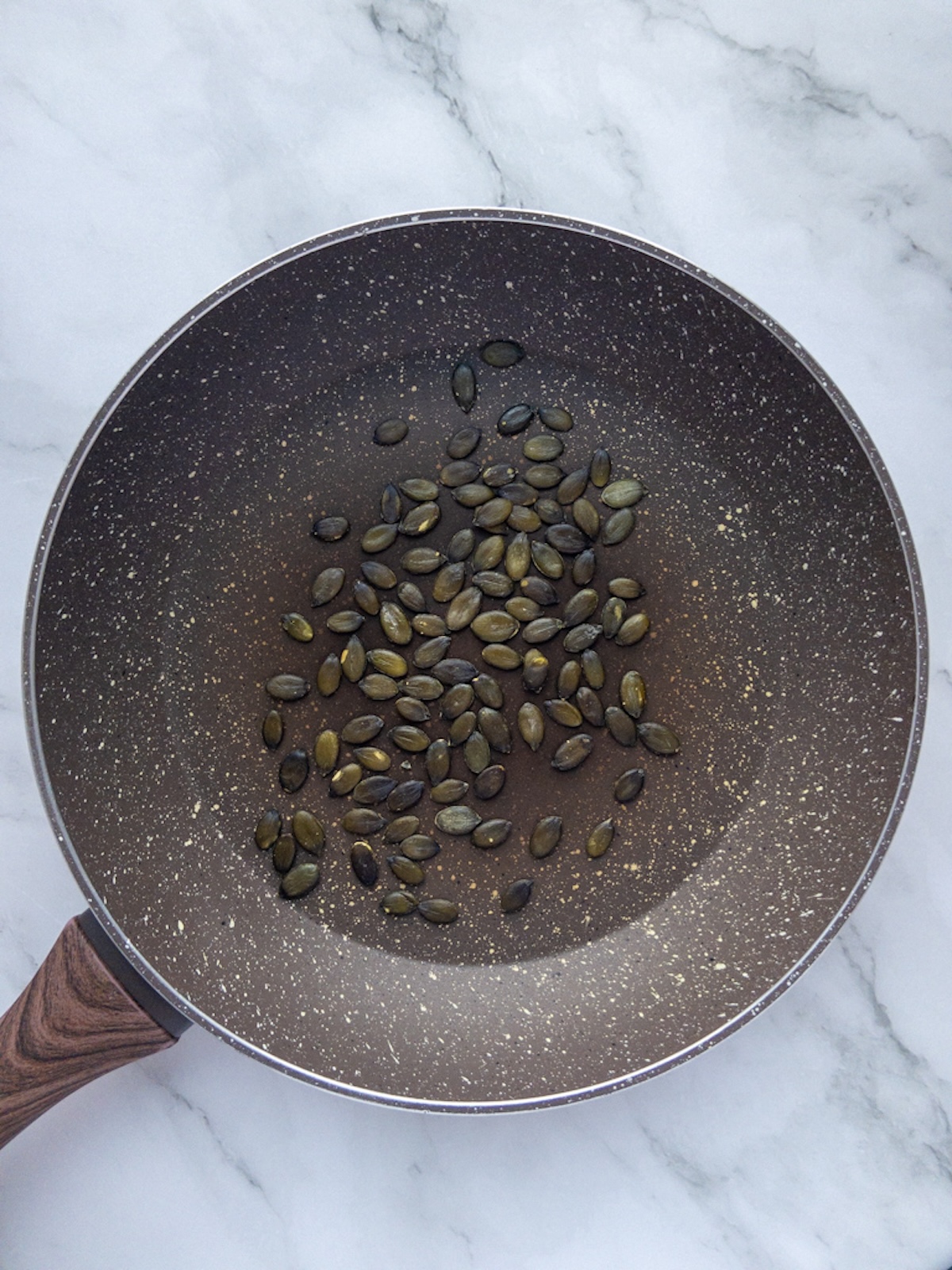 Pumpkin seeds in a pan being toasted