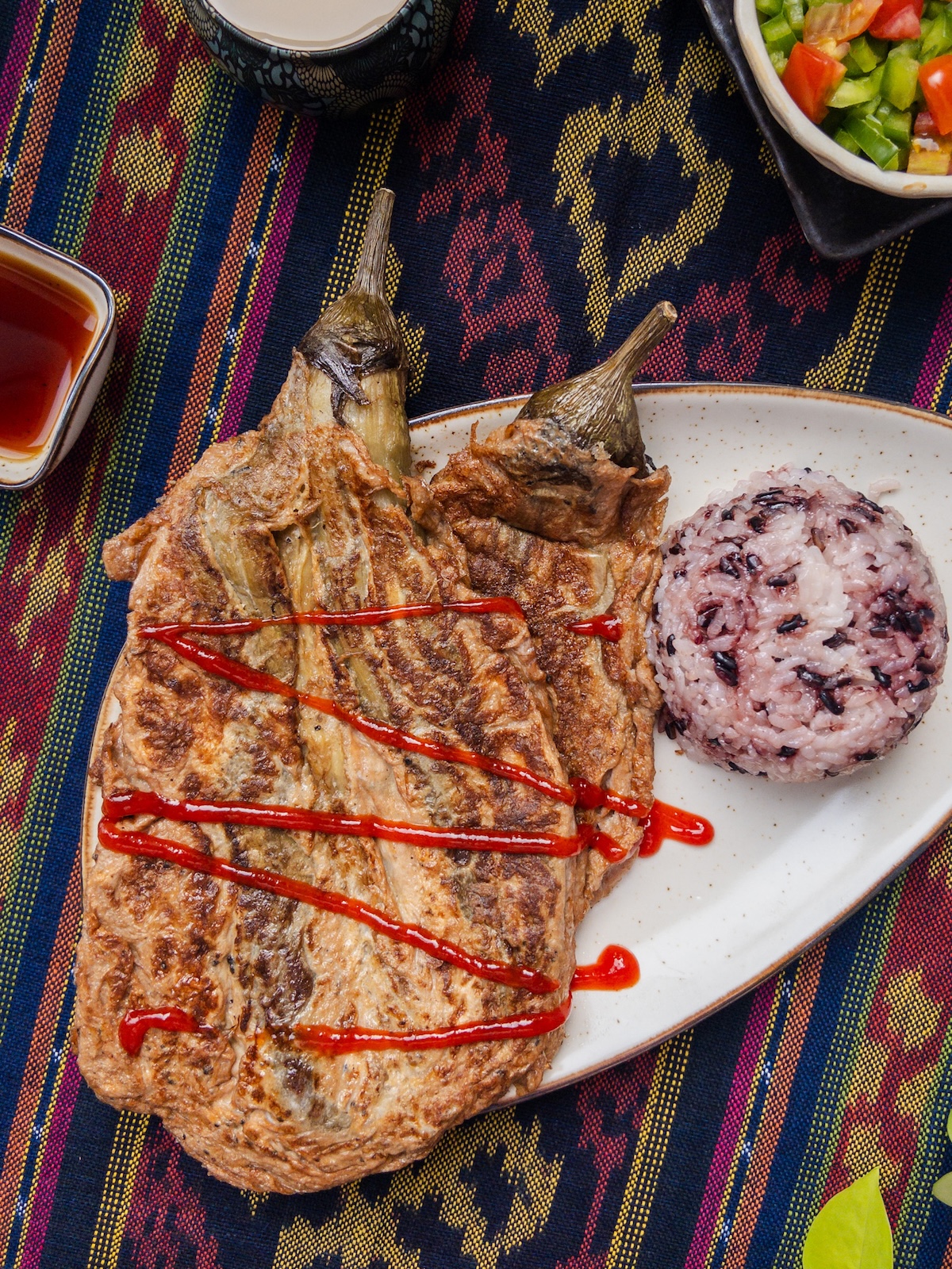 Tortang Talong, an eggplant omelette dish served with brown rice on a plate