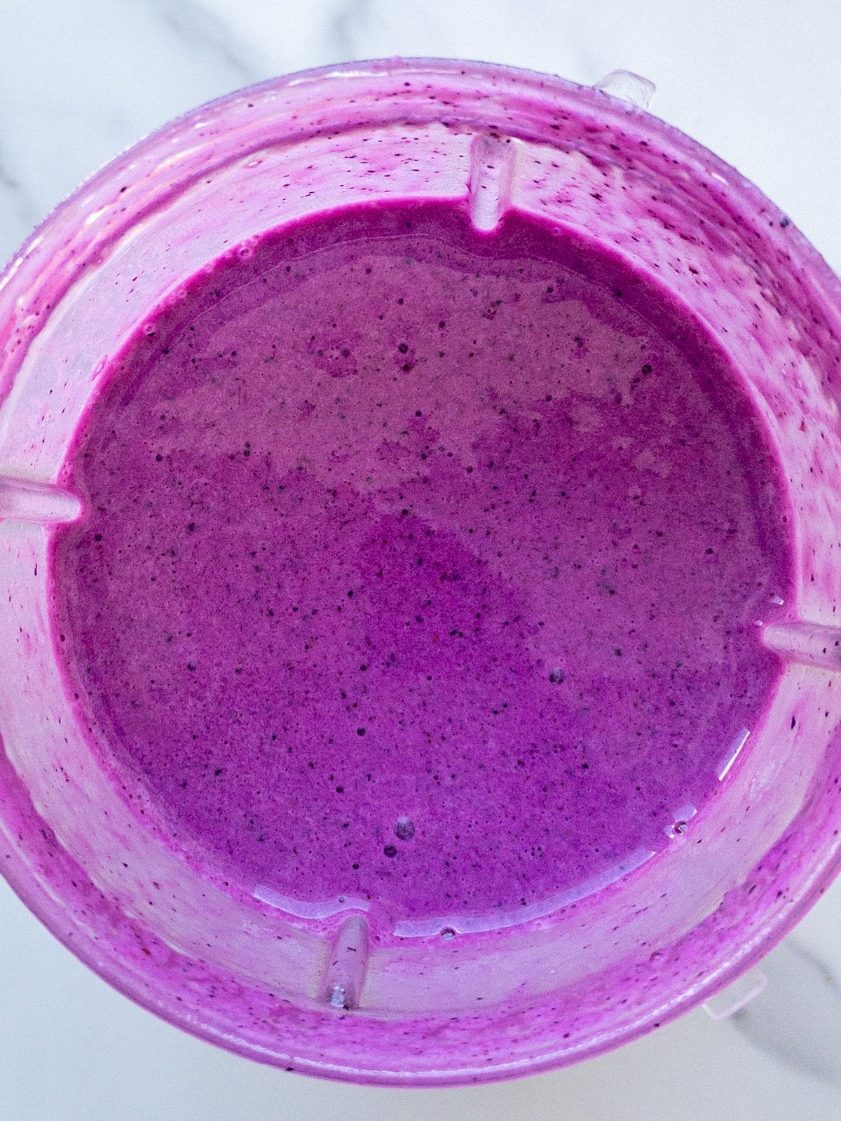 A bright pink smoothie blended in a blender