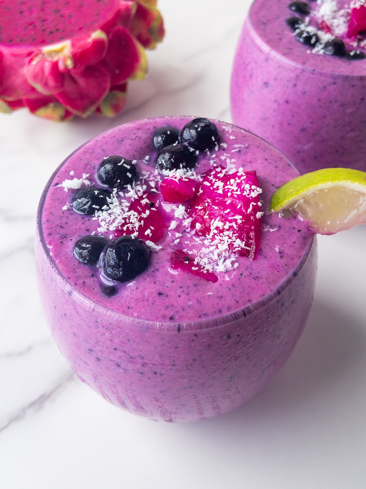 a bright pink smoothie presented in a glass topped with fresh fruit