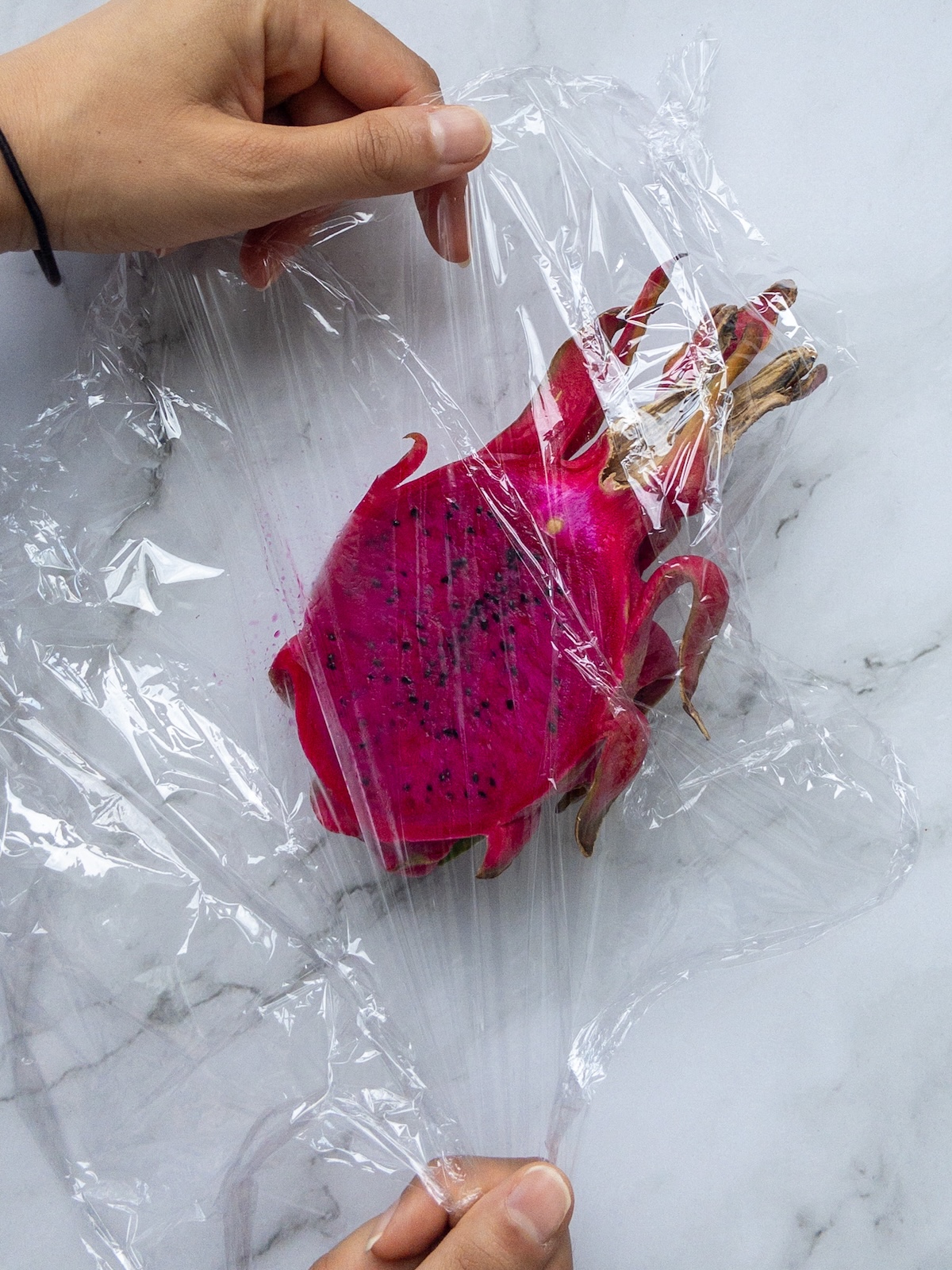 dragon fruit being wrapped in plastic wrap