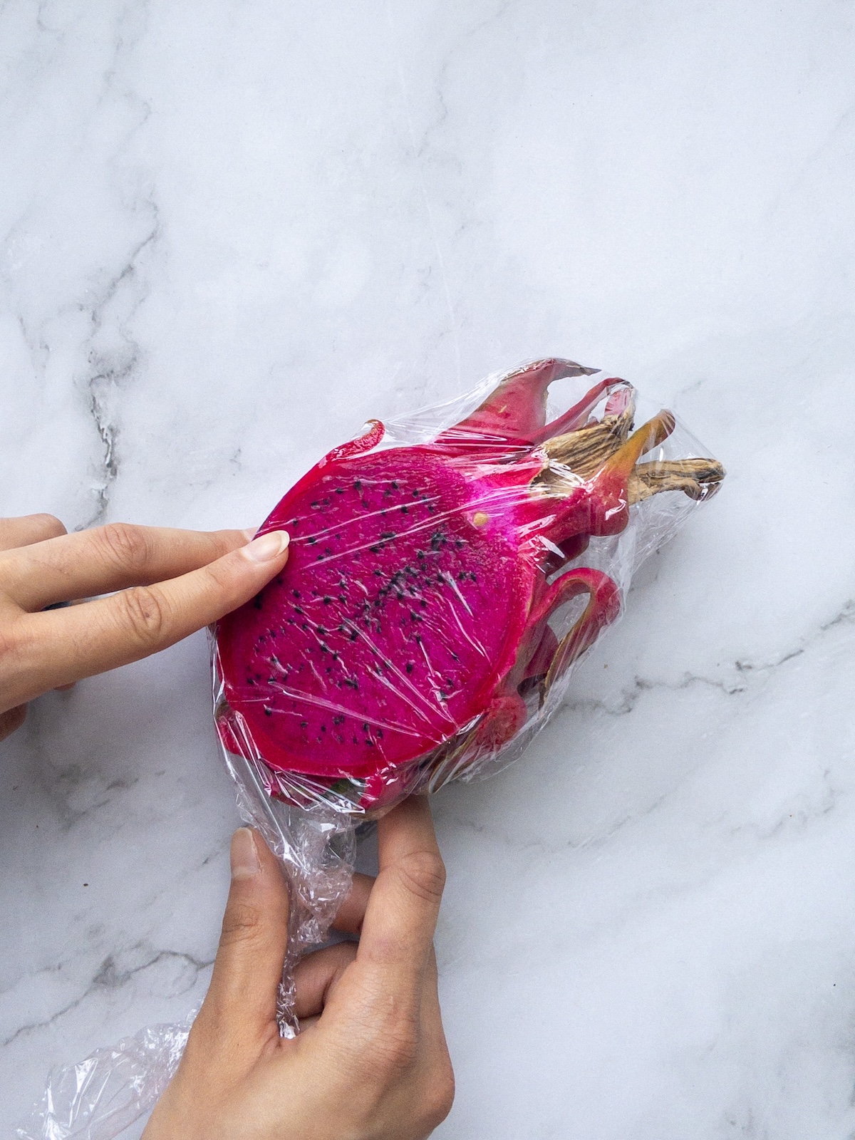 dragon fruit being wrapped in plastic wrap