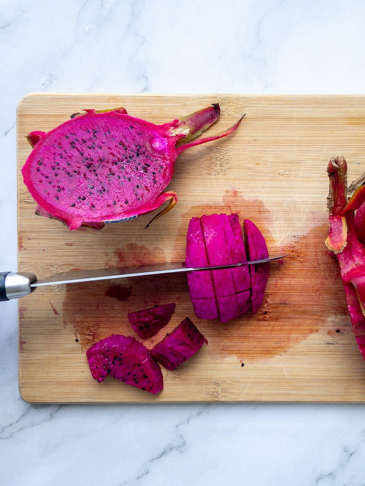 dragon fruit being cut on a wooden cutting board