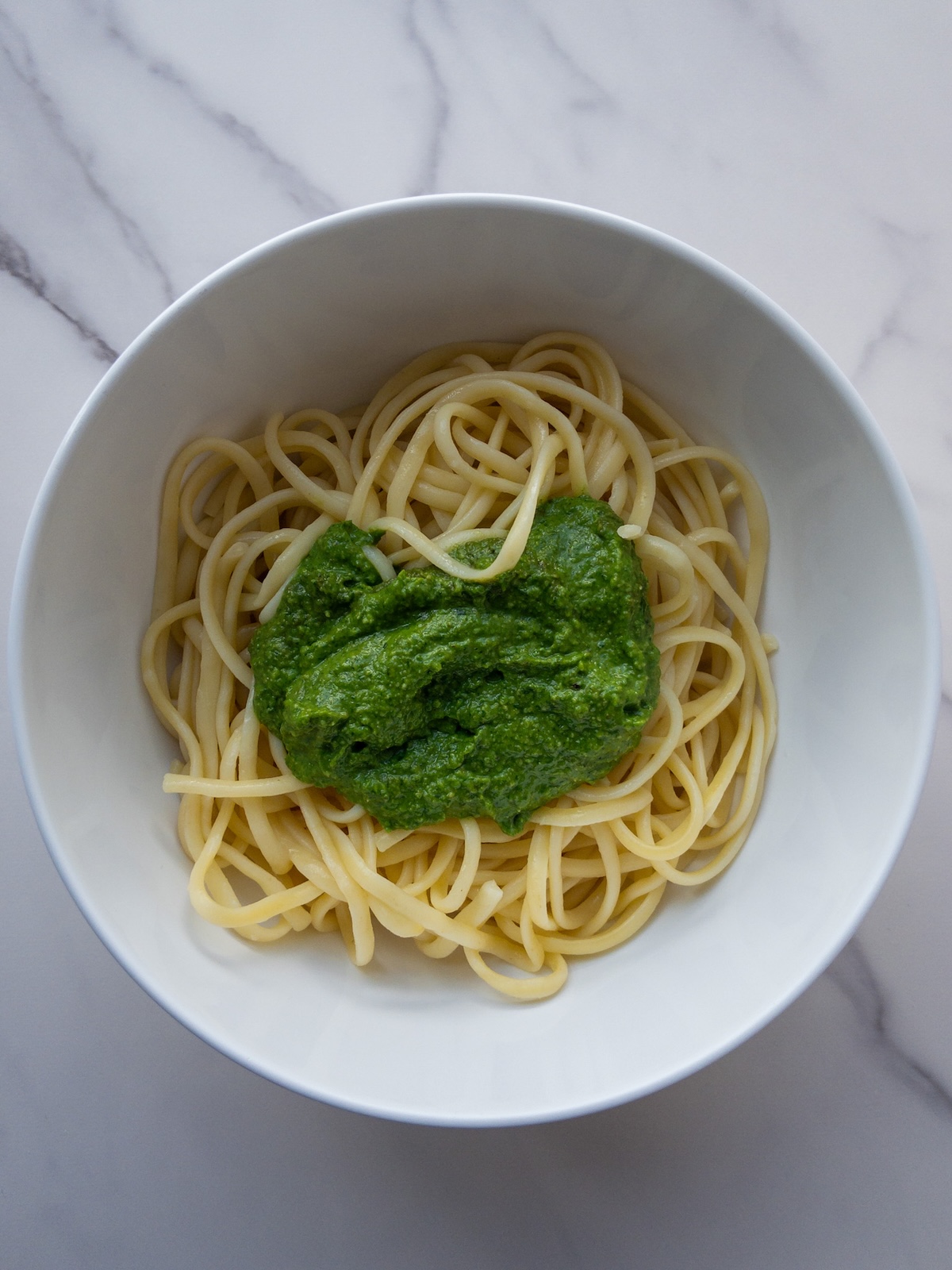 boiled linguine in a bowl with basil pesto on top