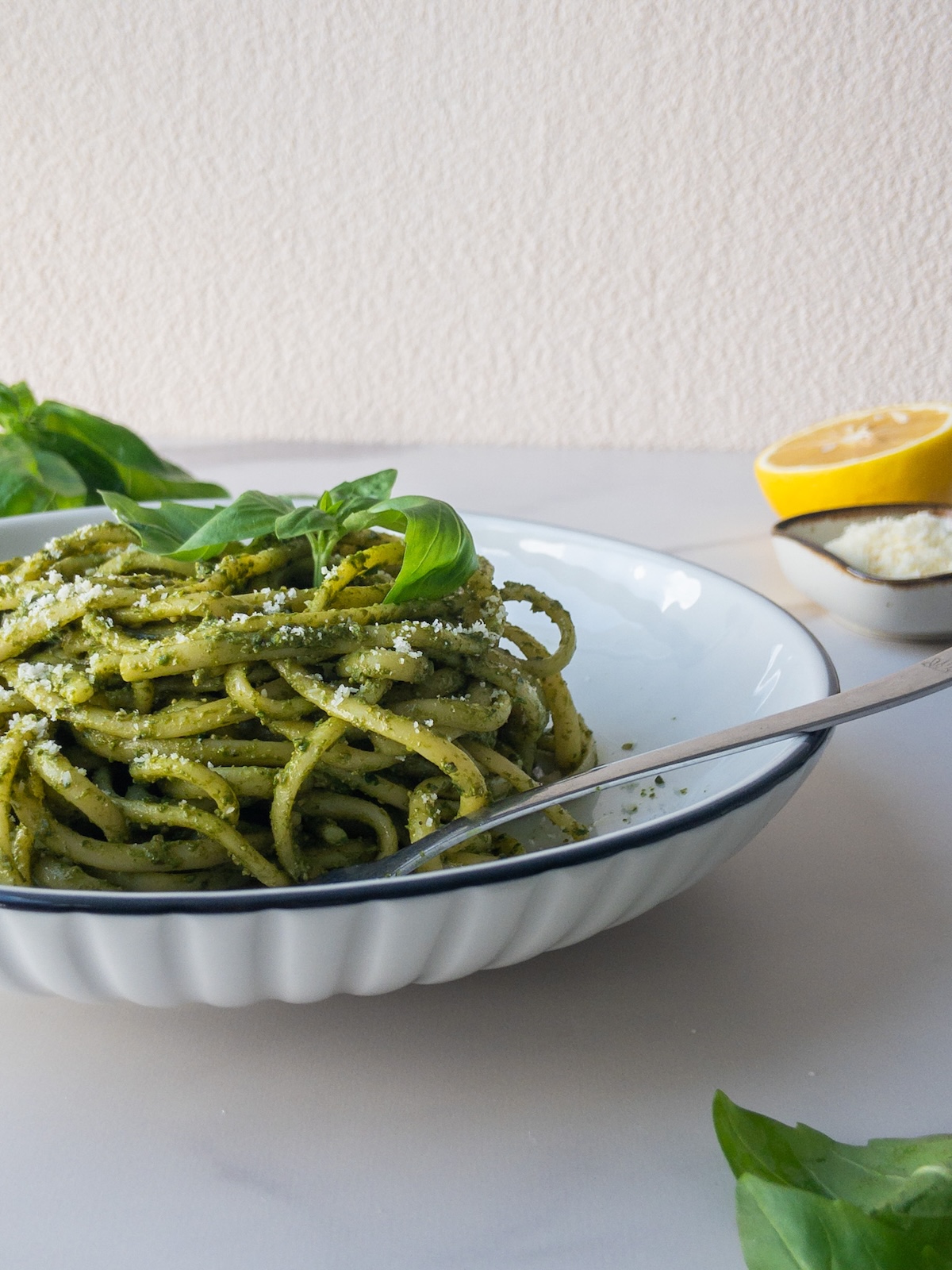 pasta with pesto served in a plate topped with fresh basil