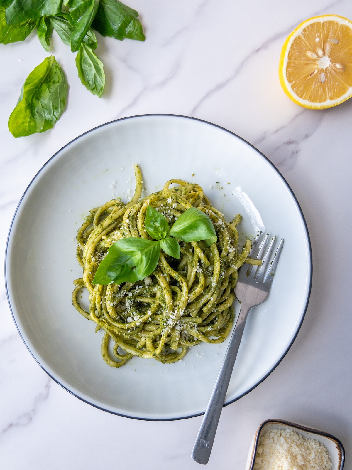 pasta with pesto served in a plate topped with fresh basil