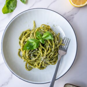 pasta with pesto served in a plate topped with fresh basil