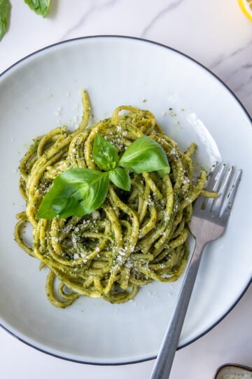pasta with pesto served in a plate topped with fresh basil