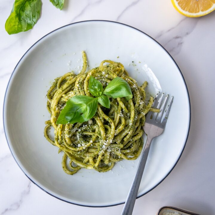 pasta with pesto served in a plate topped with fresh basil
