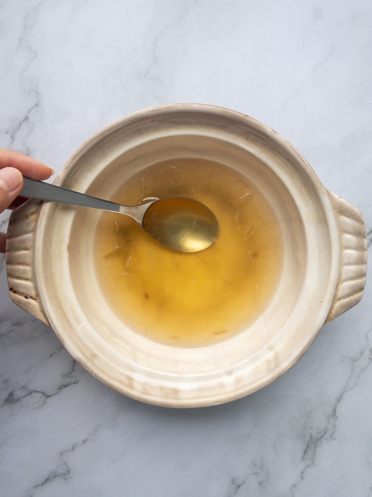 water, sugar, vegan fish sauce and lime juice being mixed in a bowl on a counter to make Nuoc Cham Chay