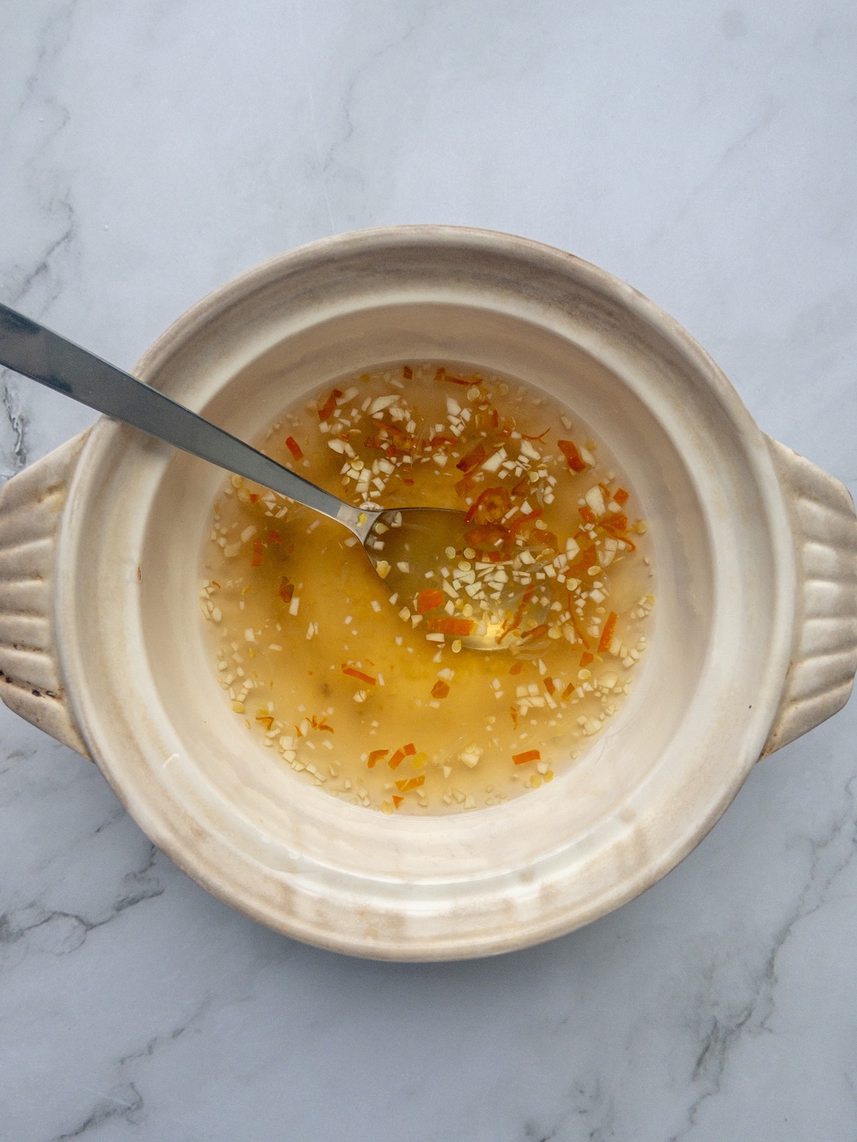 ingredients being mixed in a bowl on a counter to make Nuoc Cham Chay