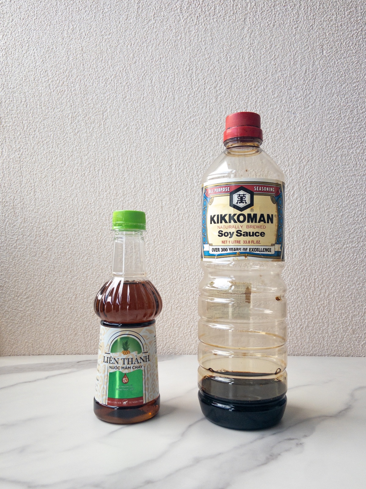 a bottle of vegan fish sauce and a bottle of soy sauce on top of a table