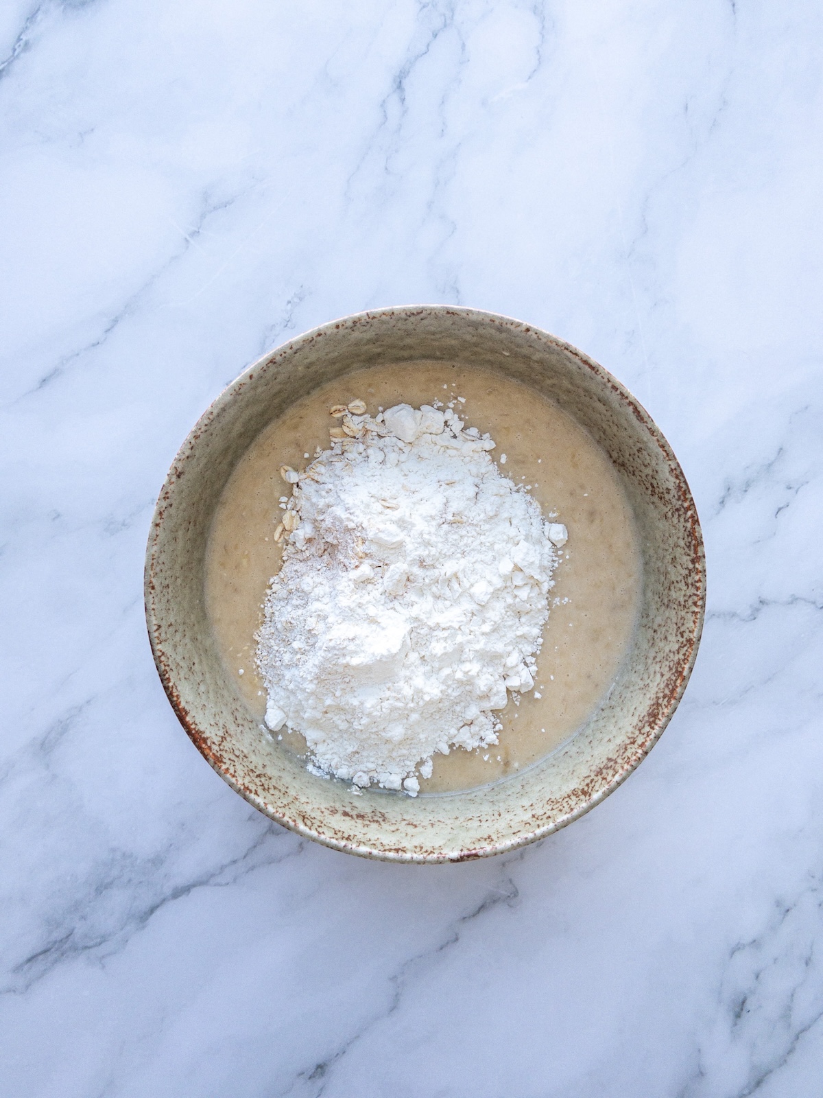 Wet and dry ingredients being mixed in a bowl for muffins