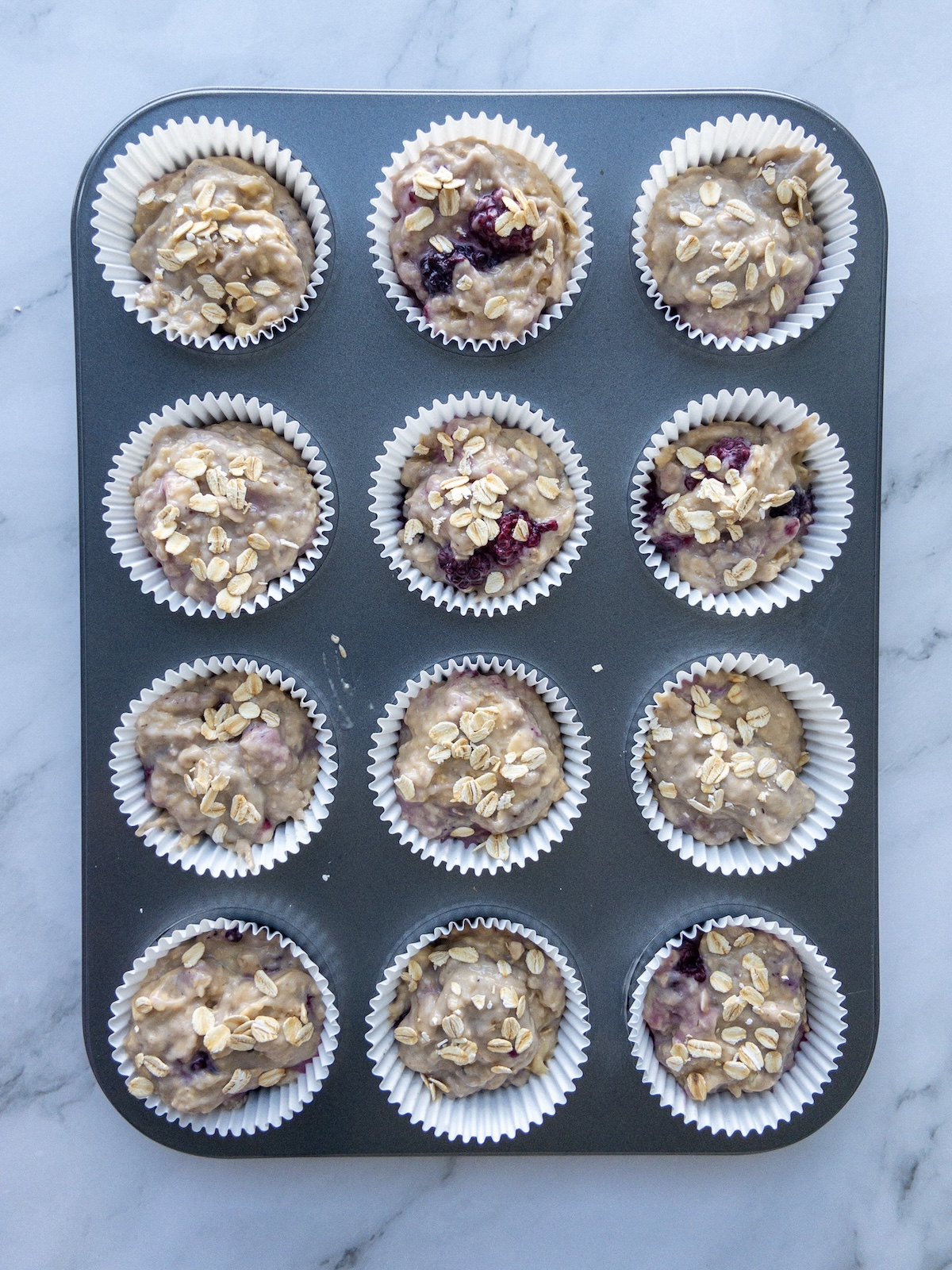 Muffin liners filled with muffin batter and topped with oats