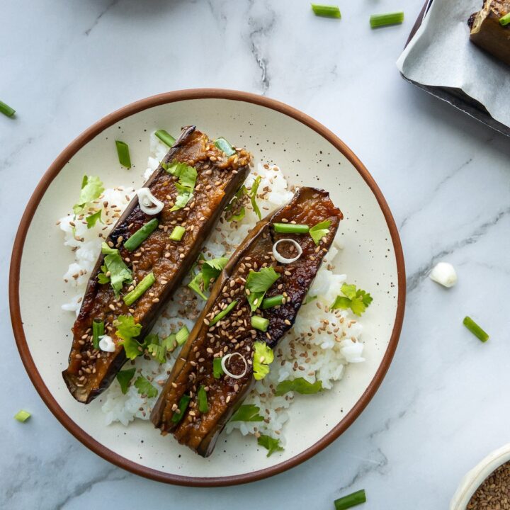 Sticky aubergines served with rice topped with sesame seeds, green onions and cilantro.