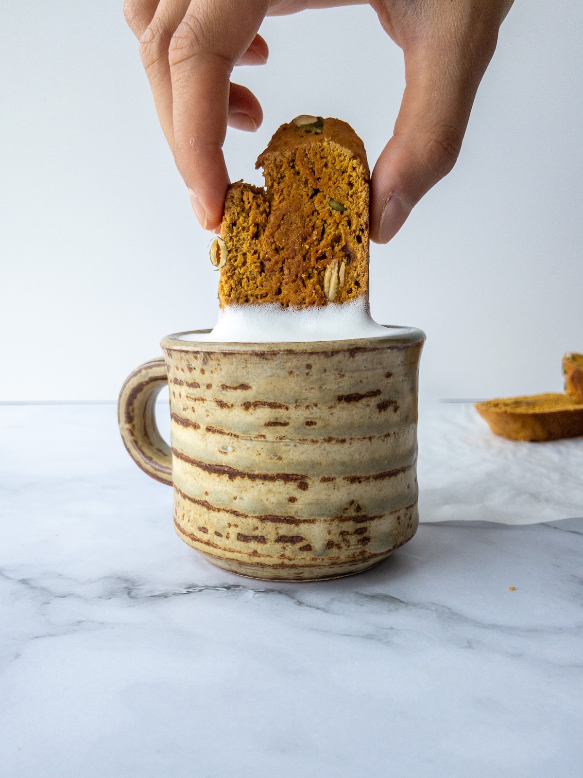 Pumpkin Biscotti being dipped in foamy milk